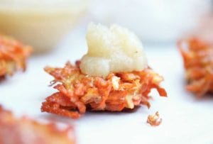 A root vegetable latke topped with a dollop of applesauce.