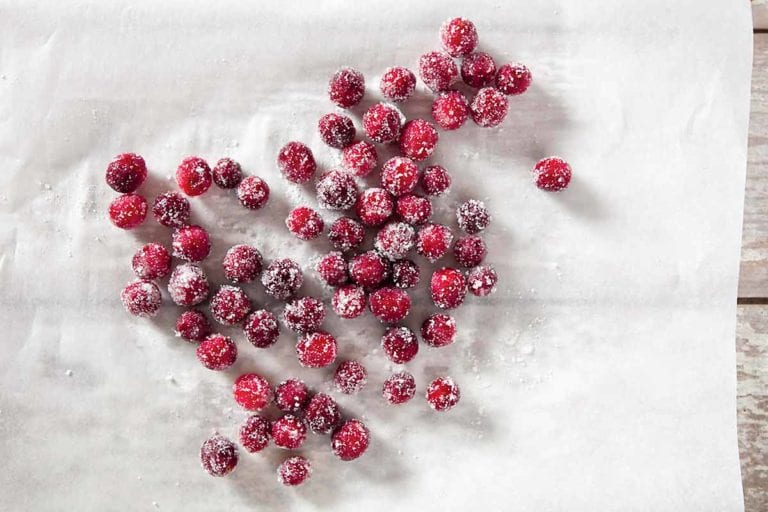 Several sugared cranberries scattered across a sheet of parchment.