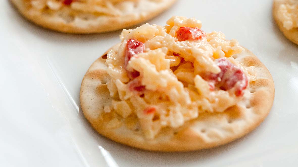 Several crackers topped with Rebecca Lang's pimento cheese--Cheddar cheese, pimentos, sweet onion, and Duke's Mayo