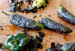 Roasted chiles piled on a wooden cutting board