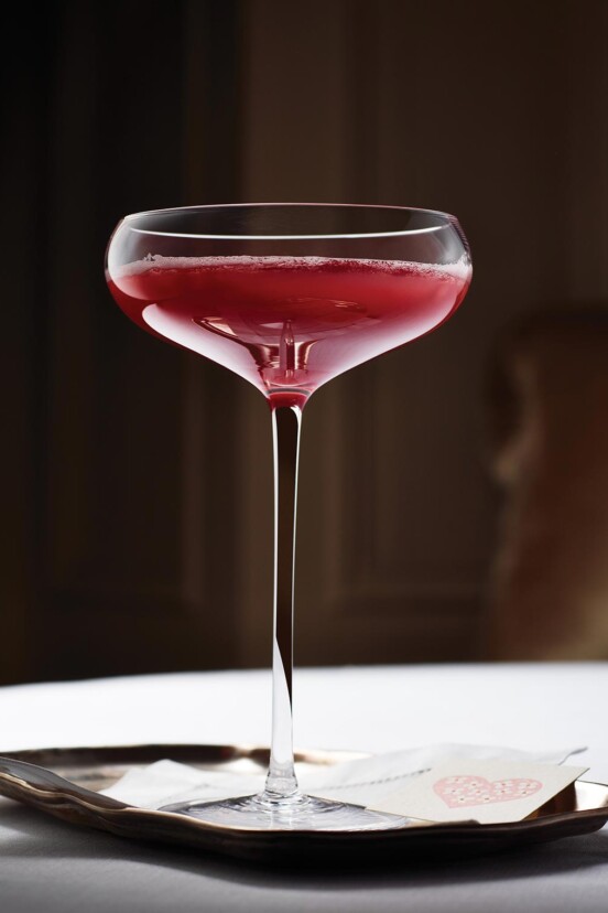 Blood orange and prosecco cocktail, in a coupe glass, on a small tray.