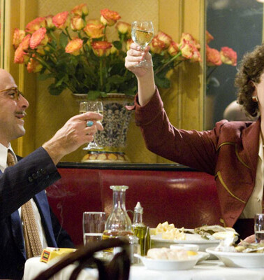 Julie and Julia toasting with wine glasses raised above a table in a restaurant.
