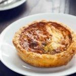 A baked mini quiche for one on a white plate.