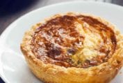 A baked mini quiche for one on a white plate.