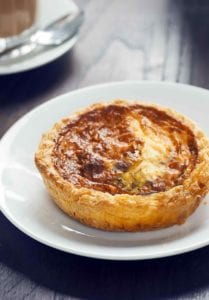 A baked mini quiche for one on a white plate.