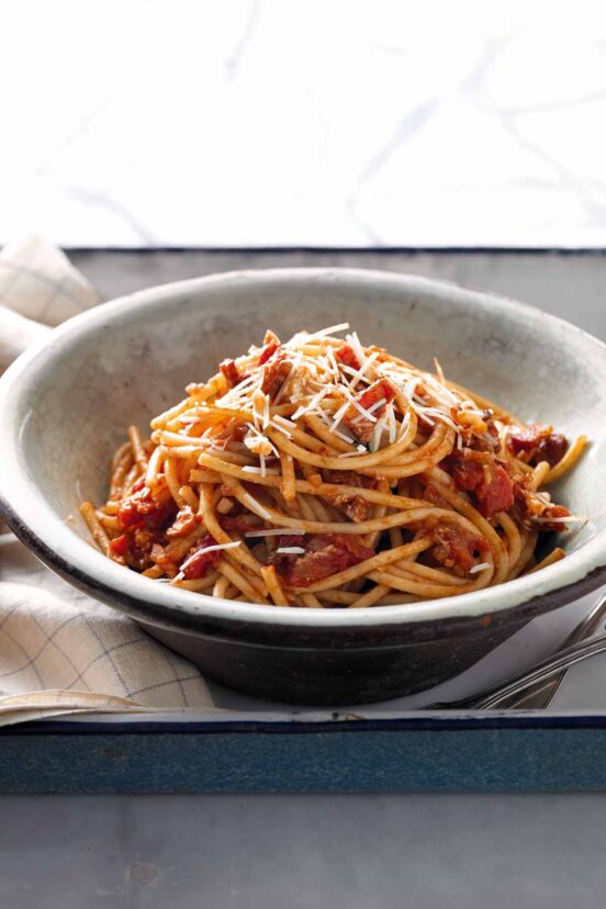 A classic pasta—bucatini with an Amatriciana sauce in a bowl. On top is a shower of cheese.