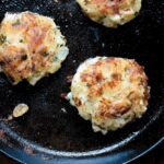 The goat cheese potato cakes in a cast iron skillet.