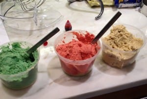 3 plastic containers of Rainbow Cookies batter colored green, red and white.