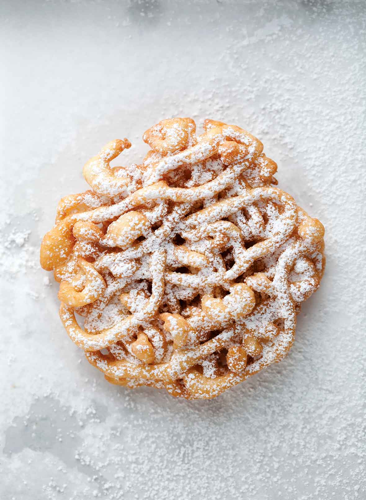 A mini funnel cake dusted with confectioners' sugar.