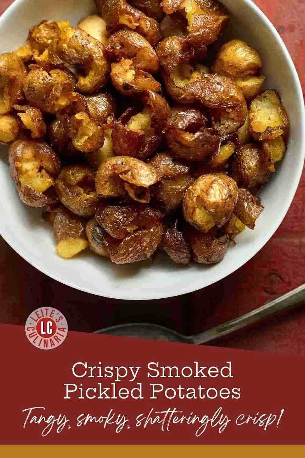 Crispy smashed smoked pickled potatoes with golden burnished skins piled high in a white ceramic bowl on a red background.