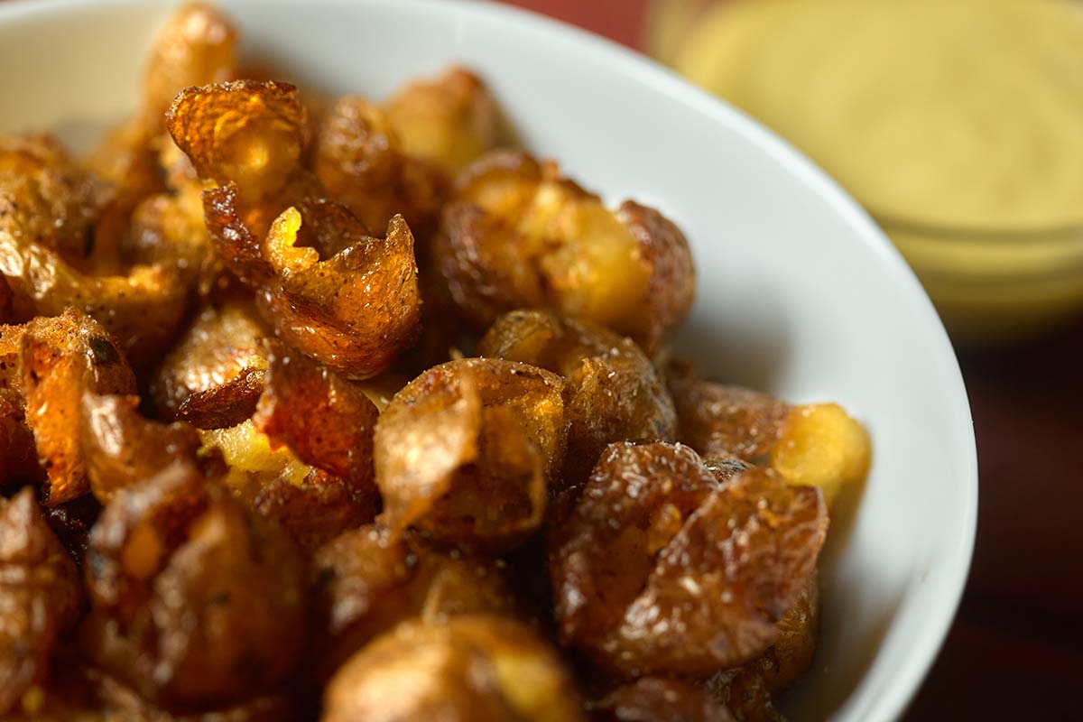A bowl filled with small round potatoes that have been pickled, smoked, and then deep-fried.