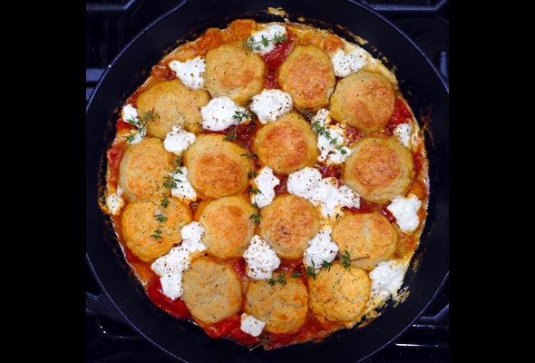 A cast-iron skillet with a finished tomato and goat cheese cobbler.