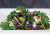 Raw kale salad on a rectangular white plate