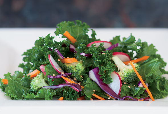 Raw kale salad on a rectangular white plate