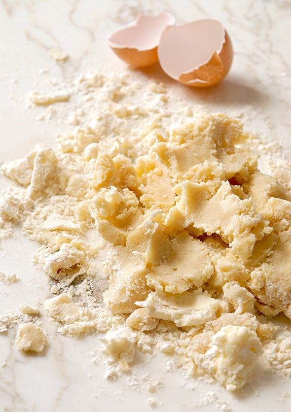 Raw pâte sablée dough with a broken egg beside it.