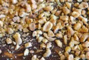 A slather of chocolate topped with chopped roasted peanuts on parchment