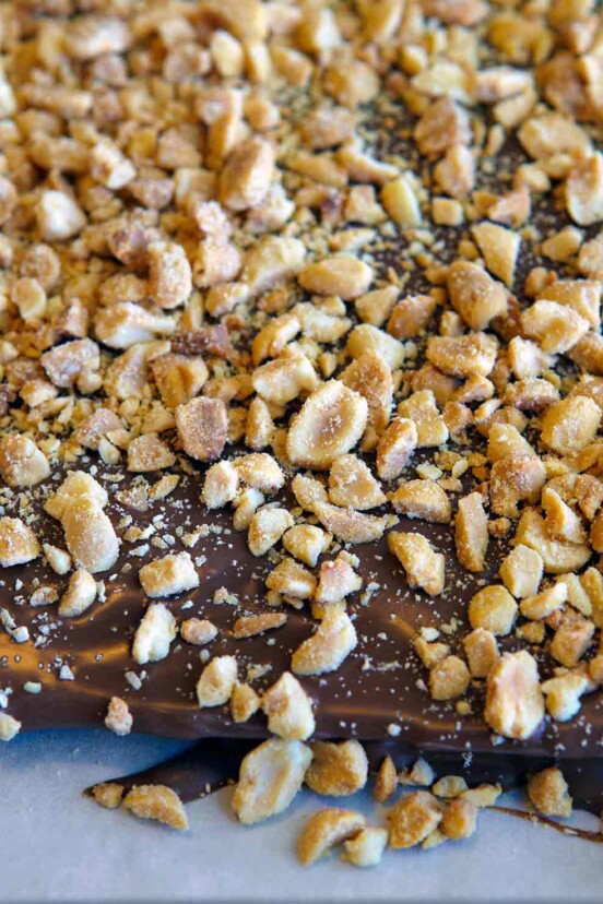 A slather of chocolate topped with chopped roasted peanuts on parchment