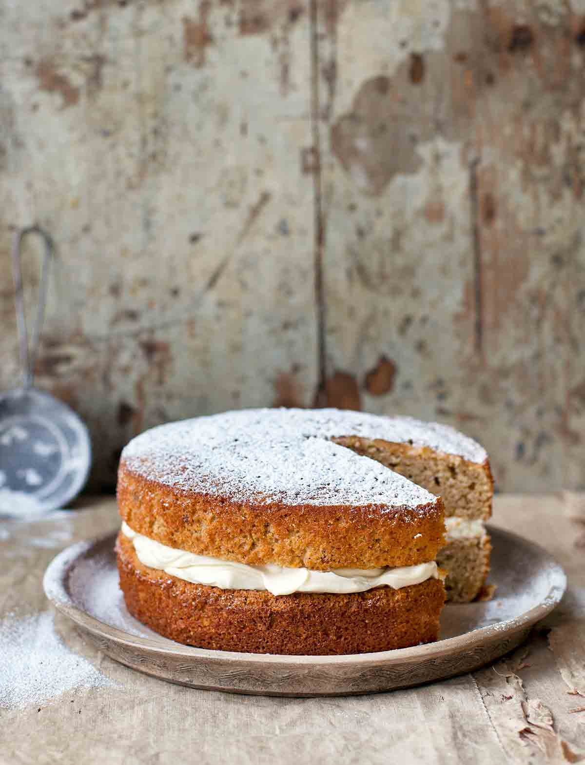 A maple parsnip cake with mascarpone frosting between the layers on a grey plate.