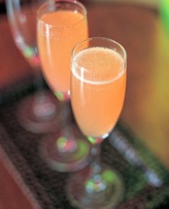 Two Champagne flutes filled with Campari fizz.