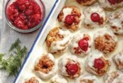 A white tray filled with Swedish meatballs--a combination of veal, pork, and beef--filled with cranberry sauce and topped with a white cream sauce
