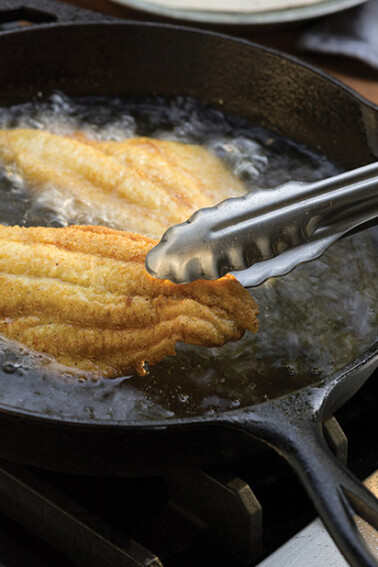 Southern fried catfish being fried in a cast-iron skillet
