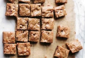 Squares of blondies with chocolate chips on parchment paper on a marble slab