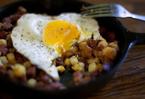 A small skillet of corned beef hash with a soft fried eggs on top