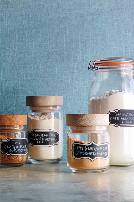 Homemade gluten-free flour in a glass storage jar along with other glass jars of other gluten-free mixes.