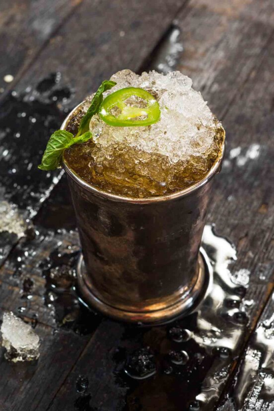 A jalapeño mint julep in a pewter julep cup, topped with a mint sprig and jalapeno slice.