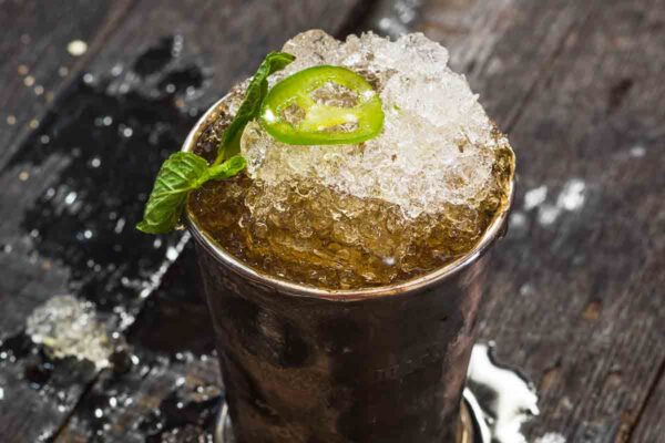 A jalapeno mint julep in a pewter julep cup, topped with a mint sprig and jalapeno slice.