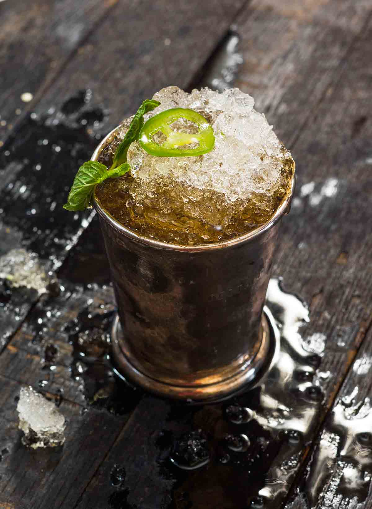 A jalapeño mint julep in a pewter julep cup, topped with a mint sprig and jalapeno slice.