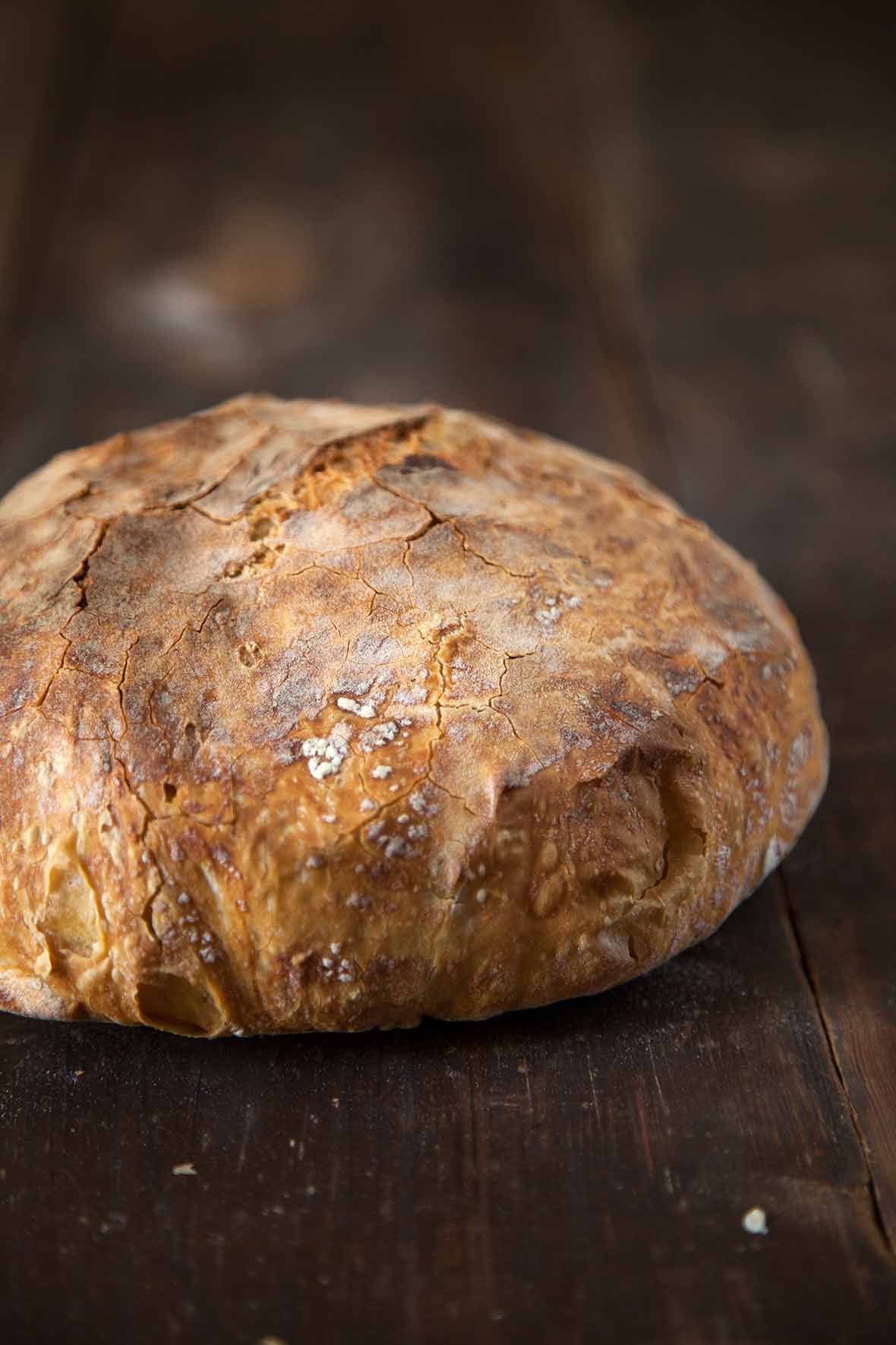 A loaf of Jim Lahey's no knead bread on a wooden board.