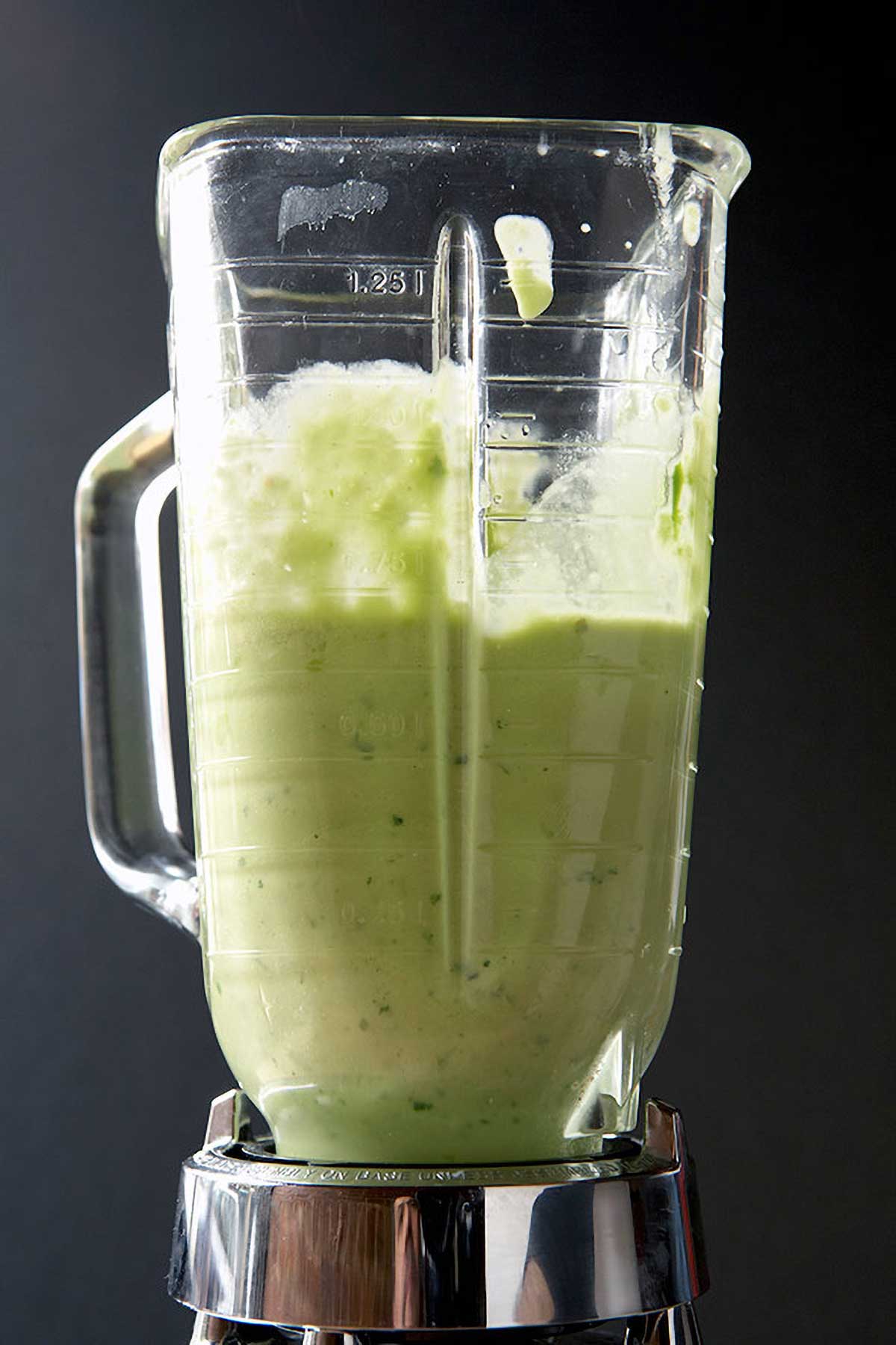 A blender half-filled with tomatillo salsa.