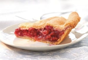 A slice of sour cherry pie on a white plate.