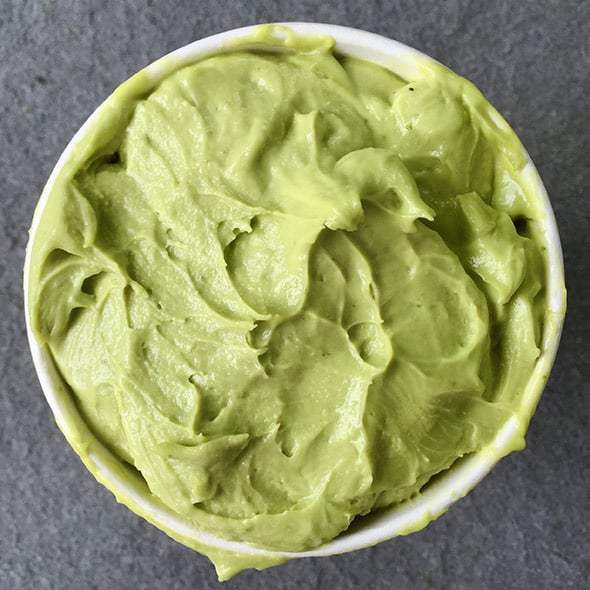 A bowl of avocado sorbet sitting on a grey counter.