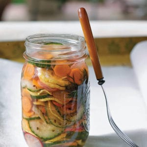 A jar of refrigerator pickles on a white napkin with a fork resting against the jar.