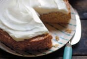 A summer squash and banana cake on a blue and white striped plate, beside a cake knife, with a slice missing.