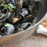 A bowl of apple cider steamed mussels topped with parsley, fries on the side