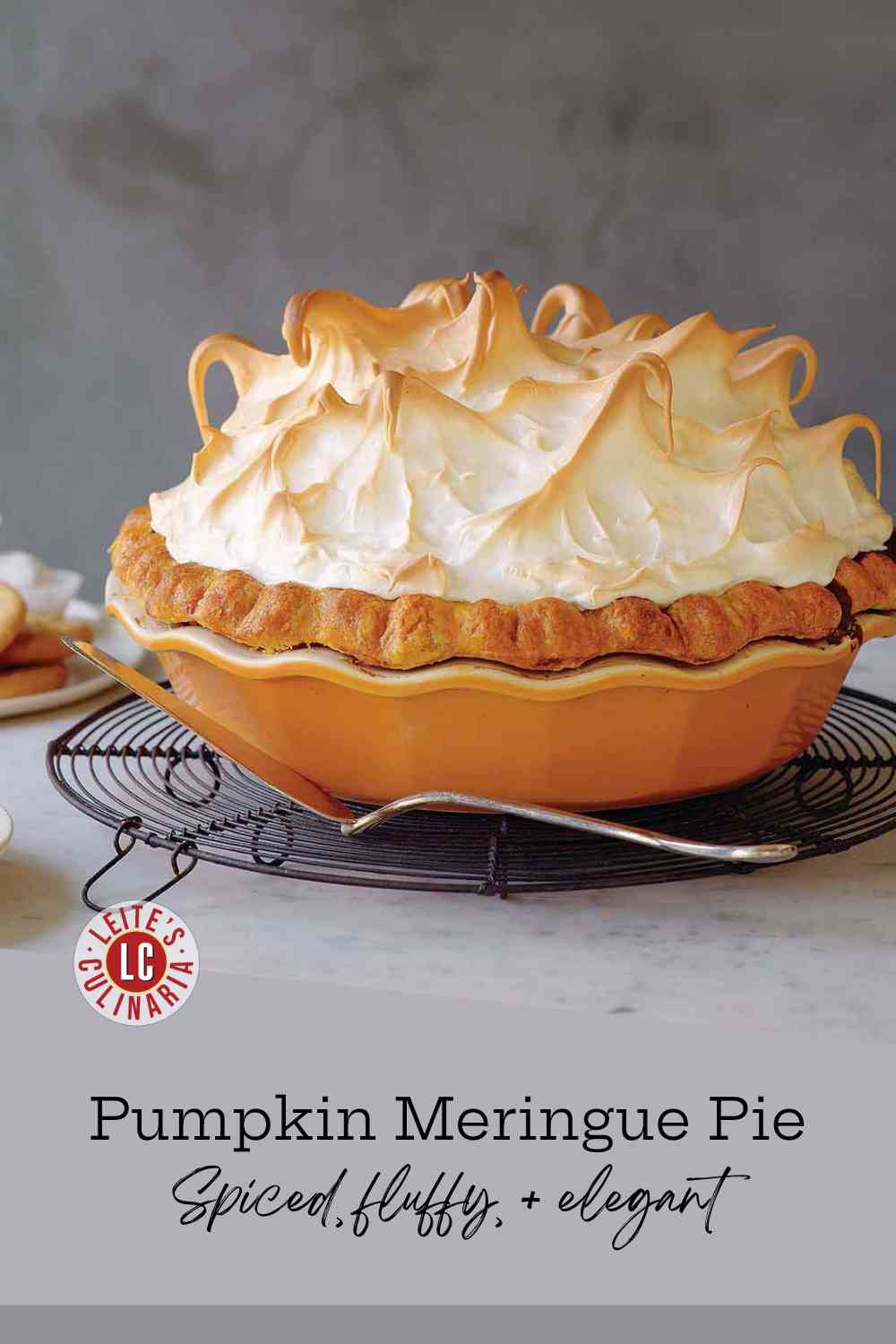 A gorgeous pumpkin pie topped with tall, toasted meringue swirls cooling on a wire rack.