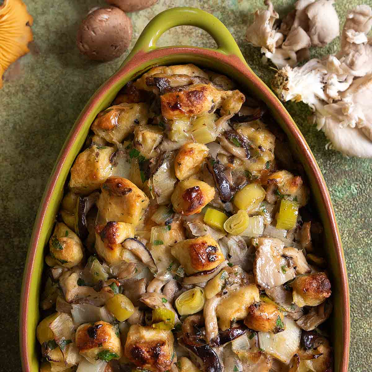 An oval casserole dish filled with wild mushroom stuffing.