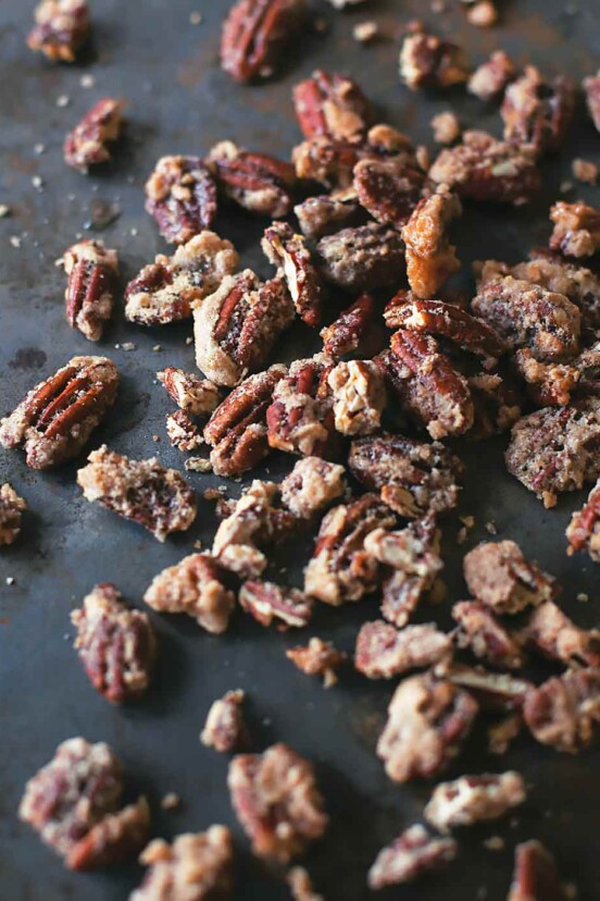 Candied pecans scattered on a dark surface.