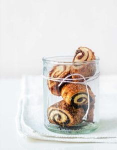 Four cream cheese rugelach in a glass jar with twine wrapped around it.