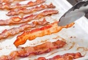 A white tray with slices of perfect baked bacon.