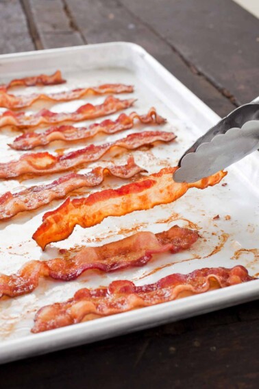 A white tray with slices of perfect baked bacon.