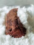 A cooked medium-rare salt-crusted beef tenderloin sitting in a pan of salt