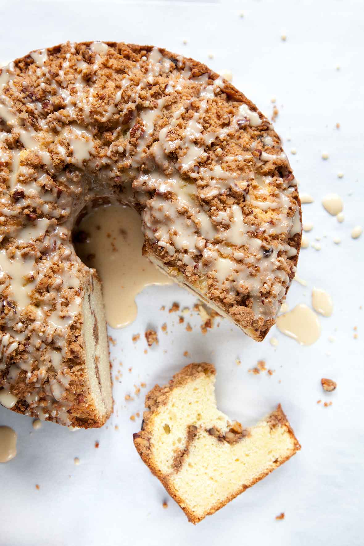 A whole sour cream coffee cake with a wedge cut from it.