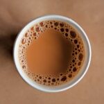 A cup of tea with milk in it on a brown background.