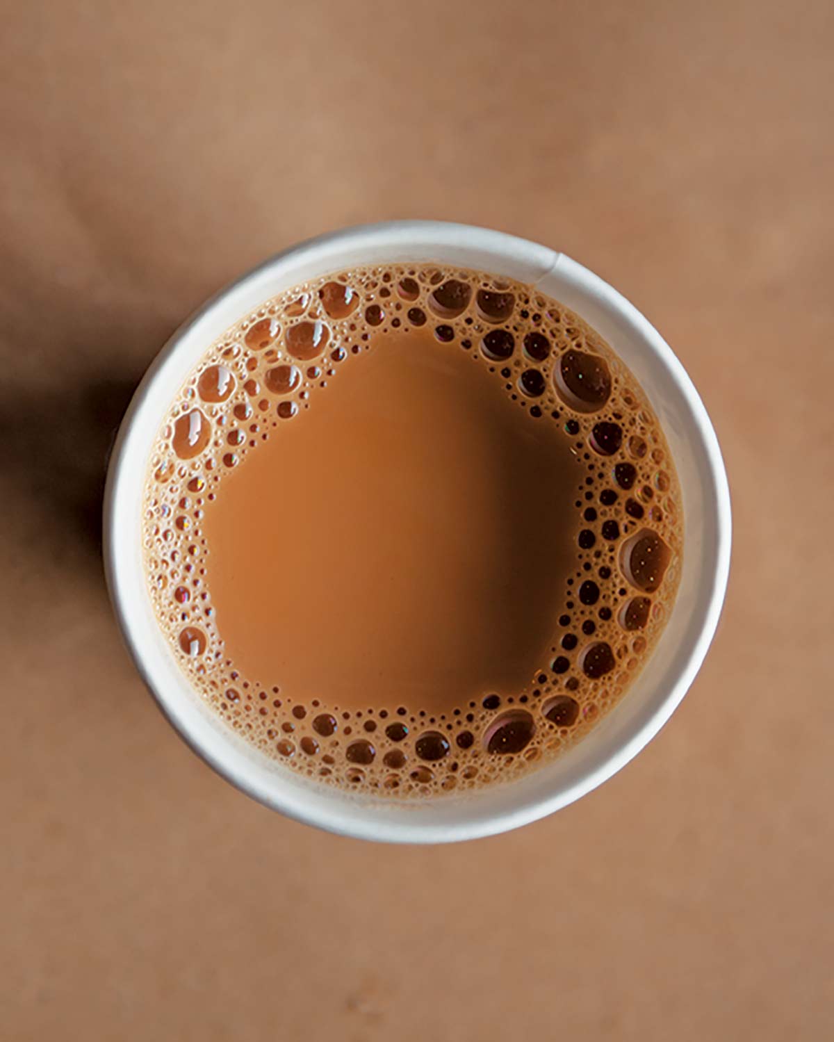 A cup of tea with milk in it on a brown background.
