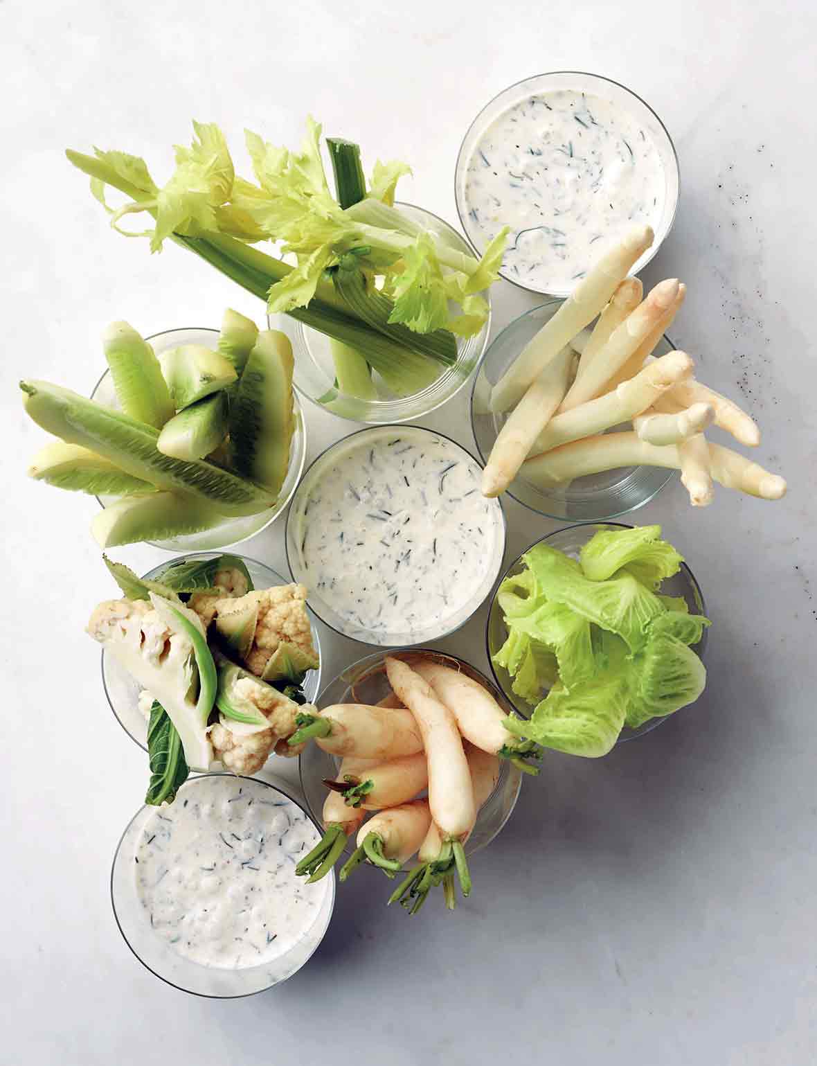 Three cups of buttermilk dressing with winter crudites in other cups.