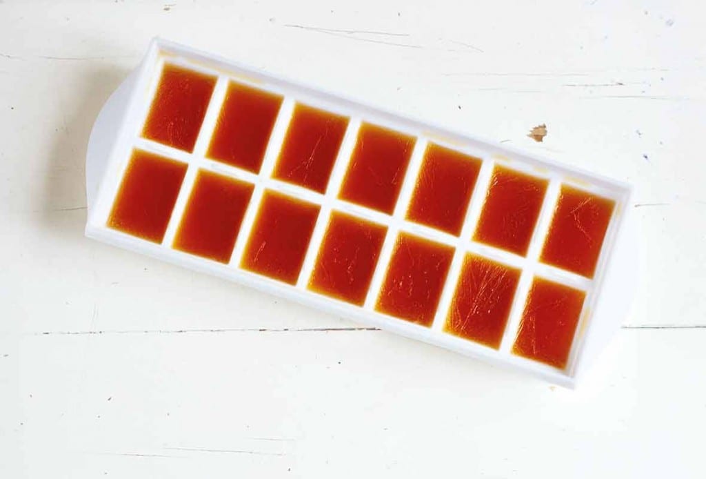 An ice cube tray filled frozen beef stock